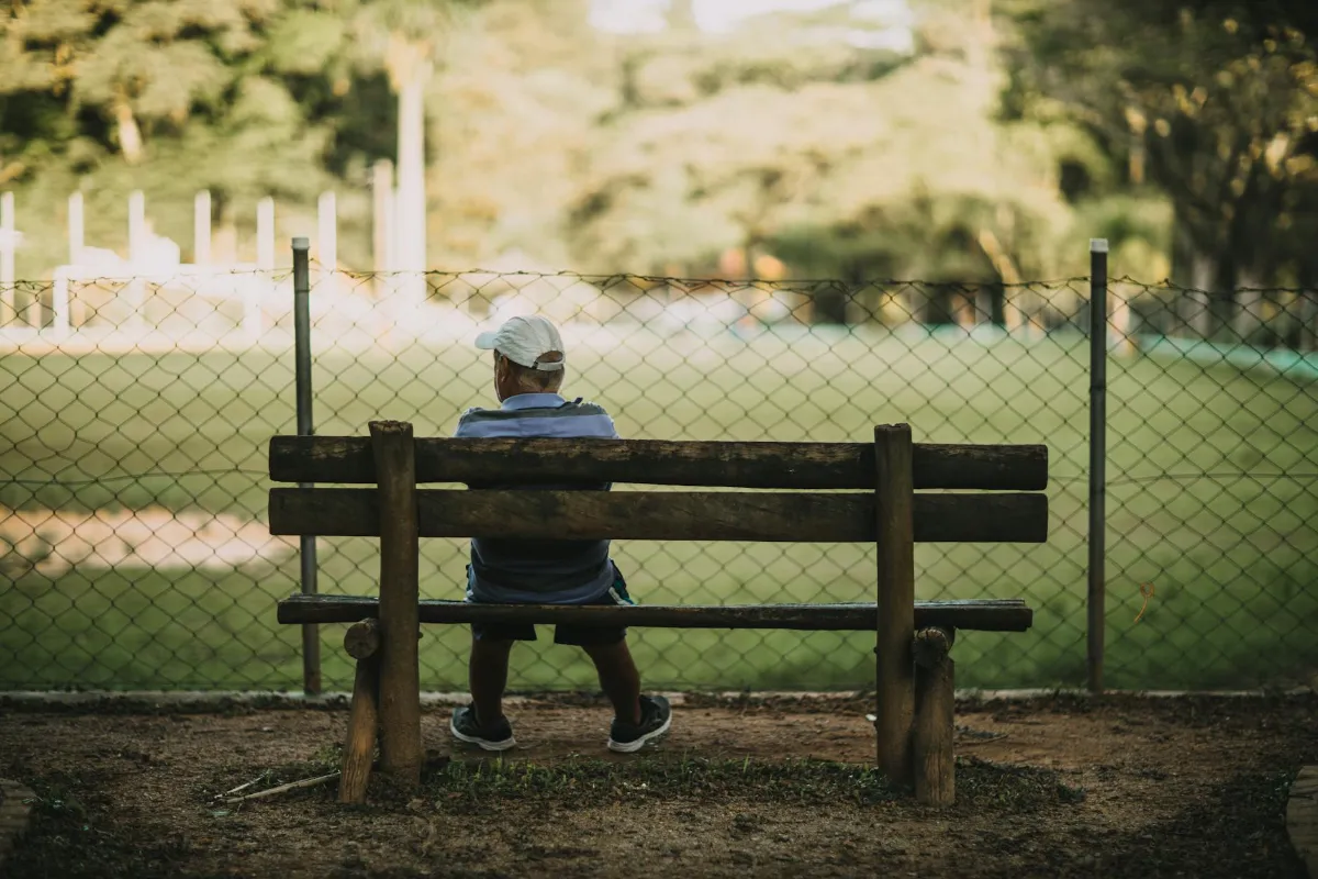 Futbolista profesional sentado en el banco del vestuario reflexionando tras su retiro deportivo