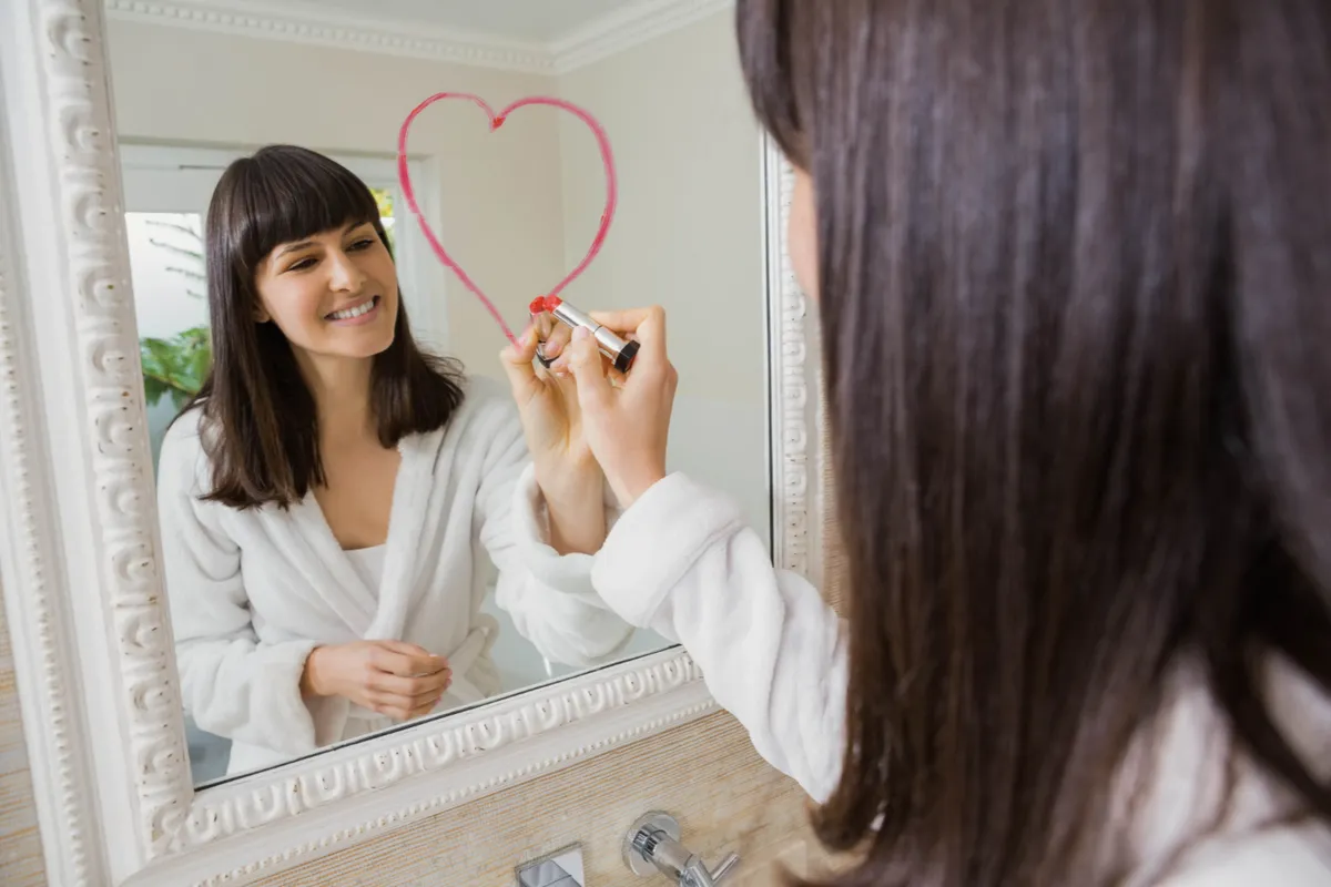 Mujer joven frente a un espejo sonriendo y practicando el diálogo interno positivo de forma consciente
