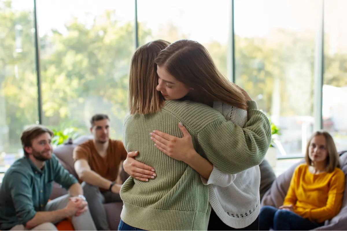 Mujer escuchando con atención y afecto a otra persona durante una conversación cercana