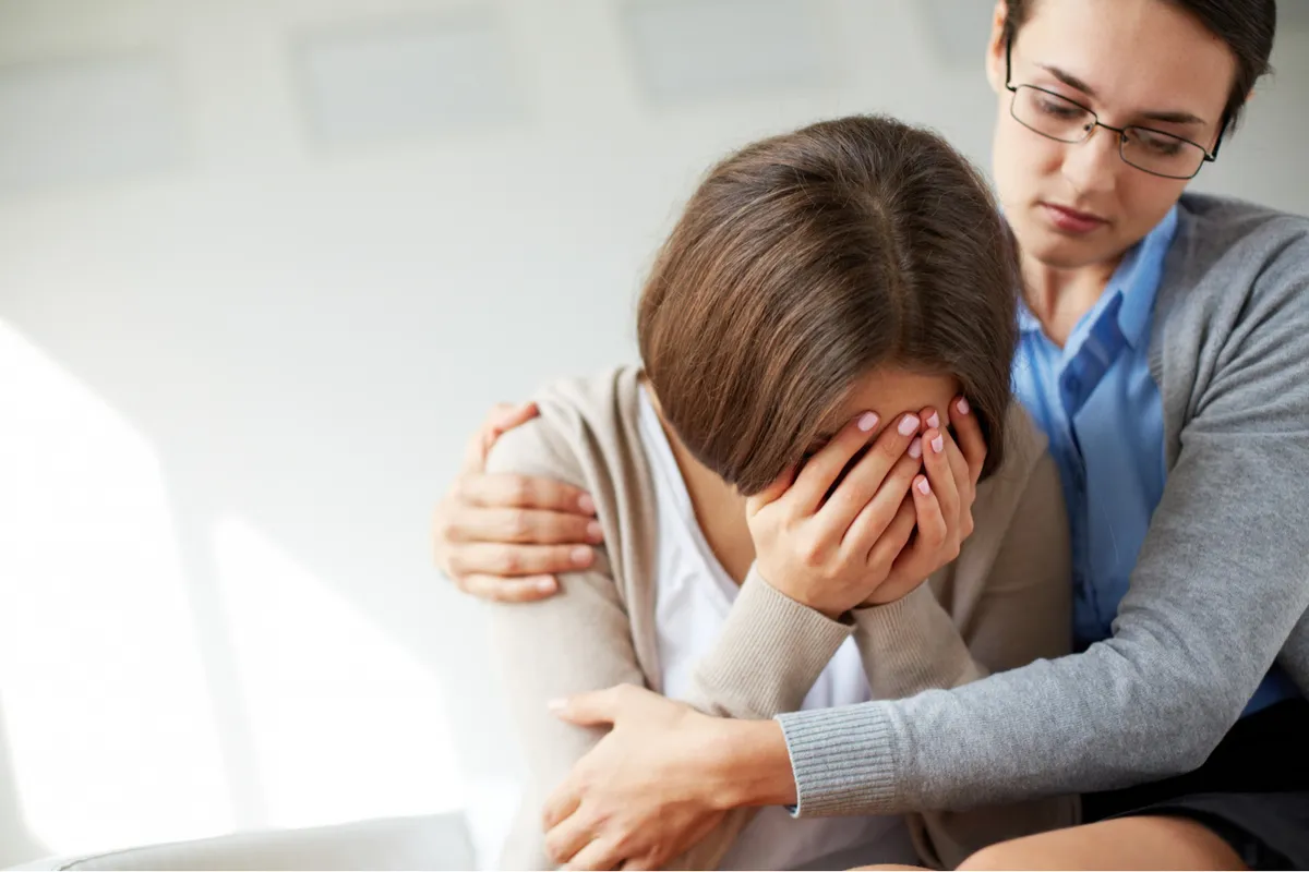 Persona sentada en un sofá con expresión de tristeza mientras otra persona ignora sus sentimientos